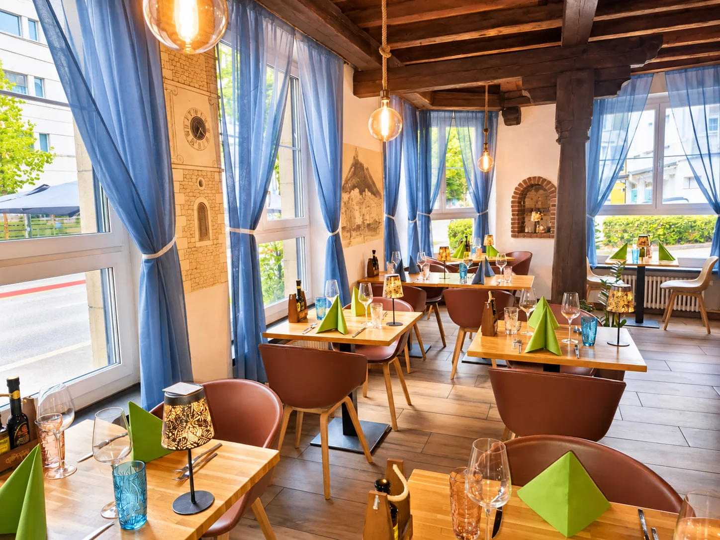 Heller Gastraum am Fenster mit blauen Vorhängen, Holzsäule und gedeckten Tischen